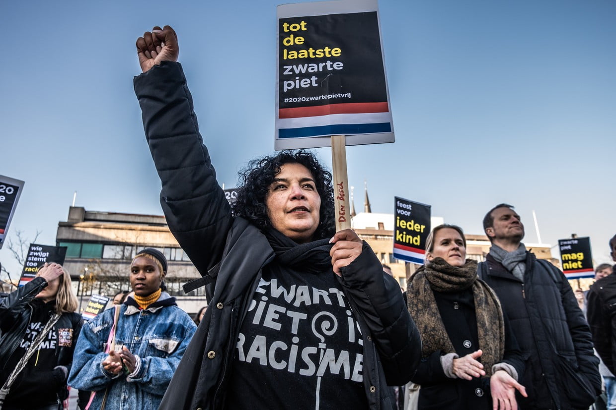 Demonstrant met geheven vuist en een bord ‘tot de laatste zwarte piet’ tijdens een protest van Kick Out Zwarte Piet.
