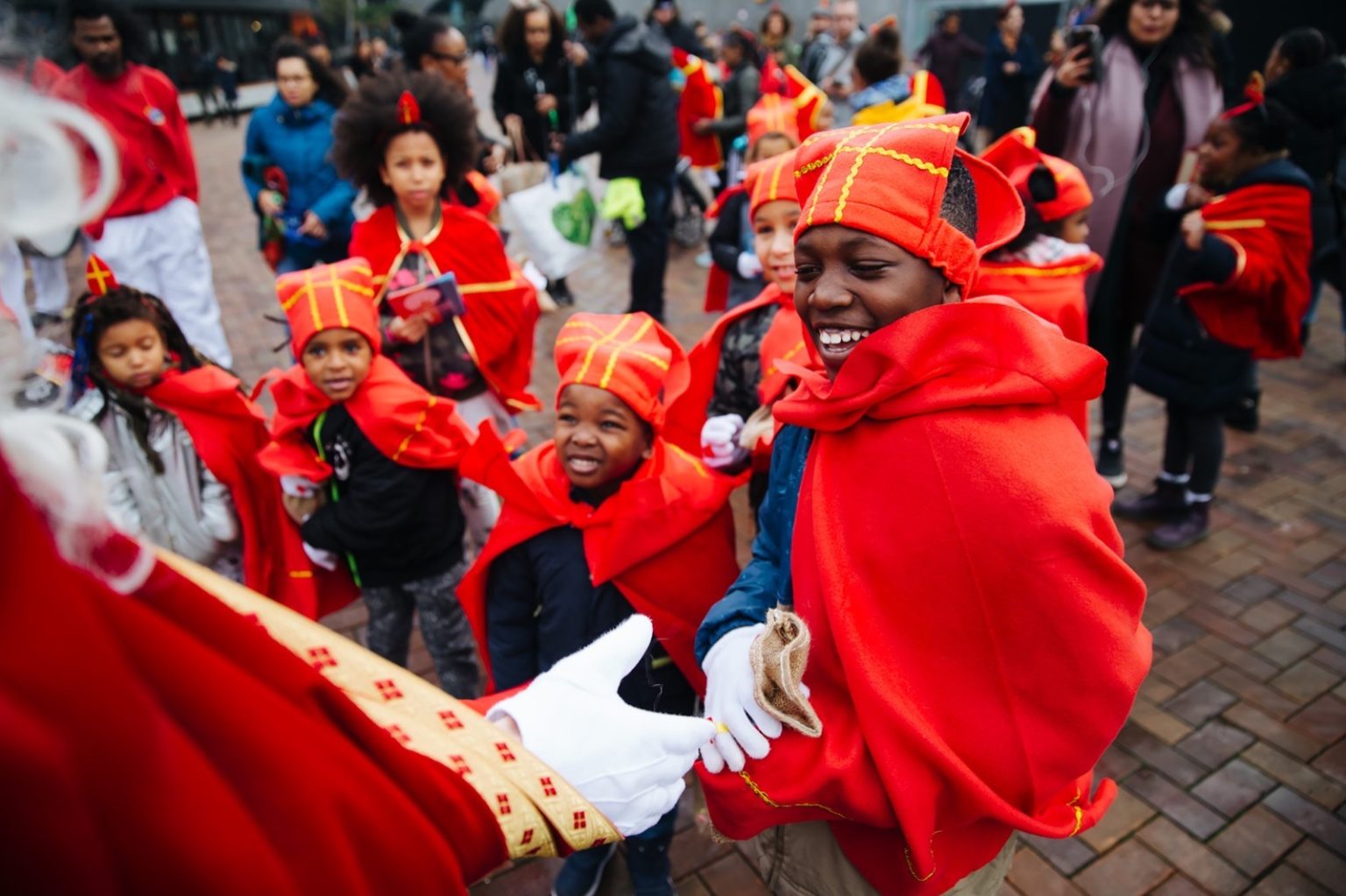 Kinderen in rode Sinterklaaspakken tijdens de inclusieve Sinterklaasintocht in Amsterdam-Zuidoost.